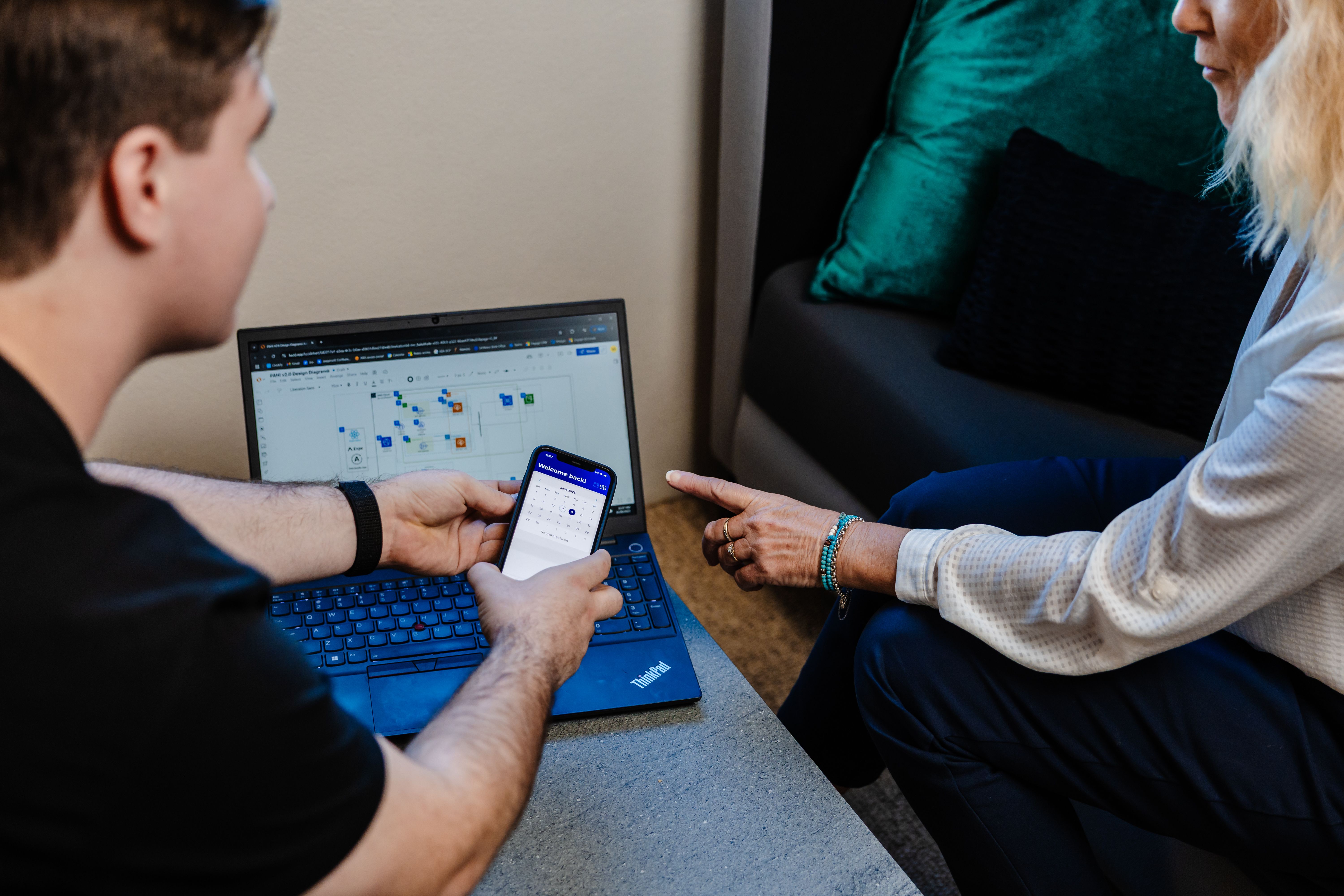 two people looking at a computer and phone